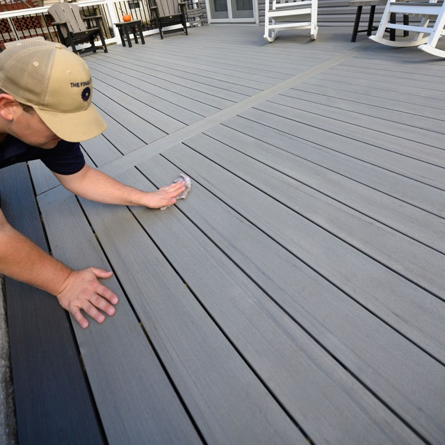 Homeowner cleaning composite deck boards during maintenance on a newly built deck in Maryland