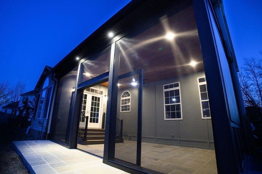  Custom screened porch with integrated lighting, dark wrapped posts, and stone flooring in Columbia, MD.